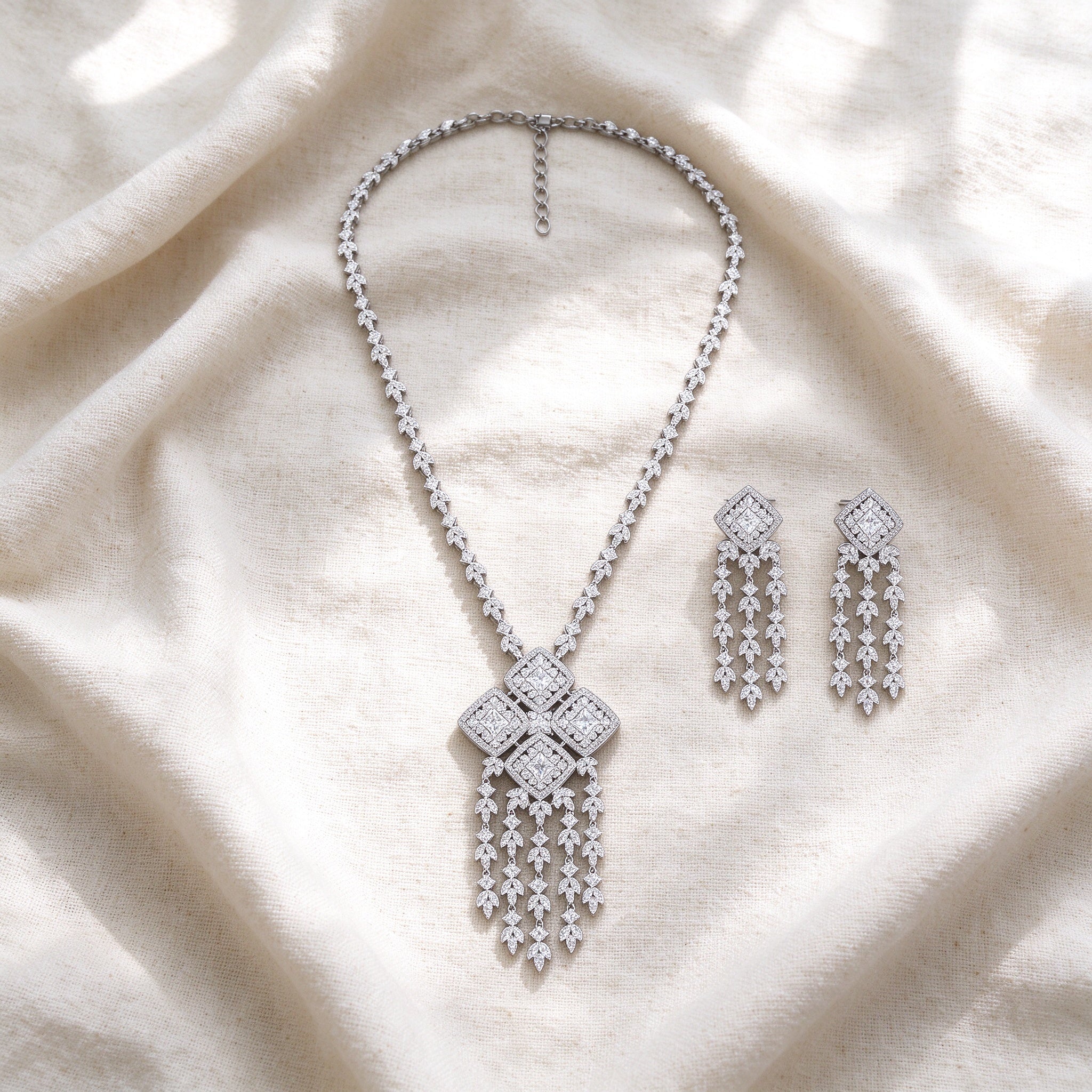Flat lay of The Aster Bridal Set — long tassel necklace and matching earrings arranged on ivory linen