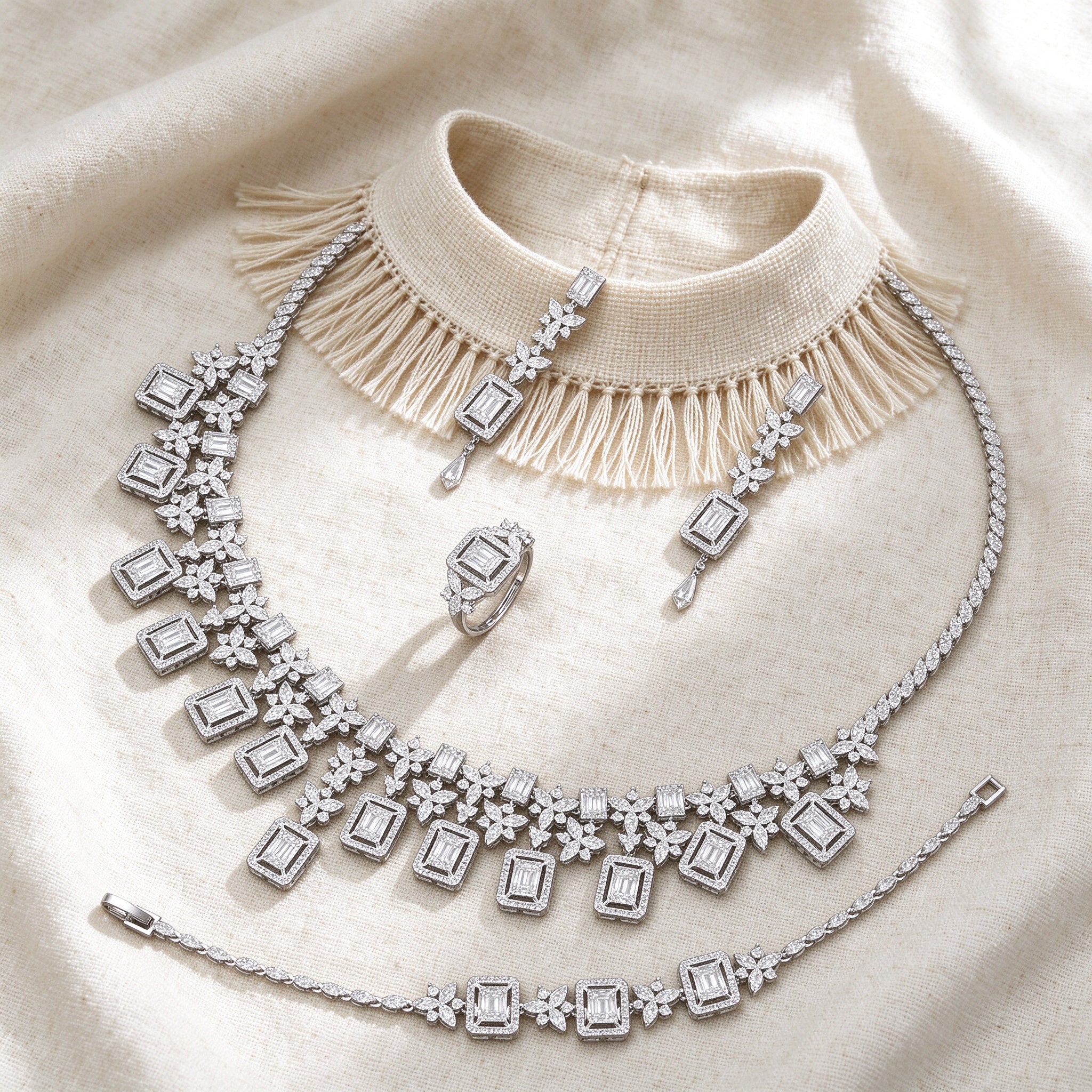 Top-down flat lay of The Aurora Wedding Suite two-piece Art-Deco emerald-cut CZ bridal set on warm ivory linen