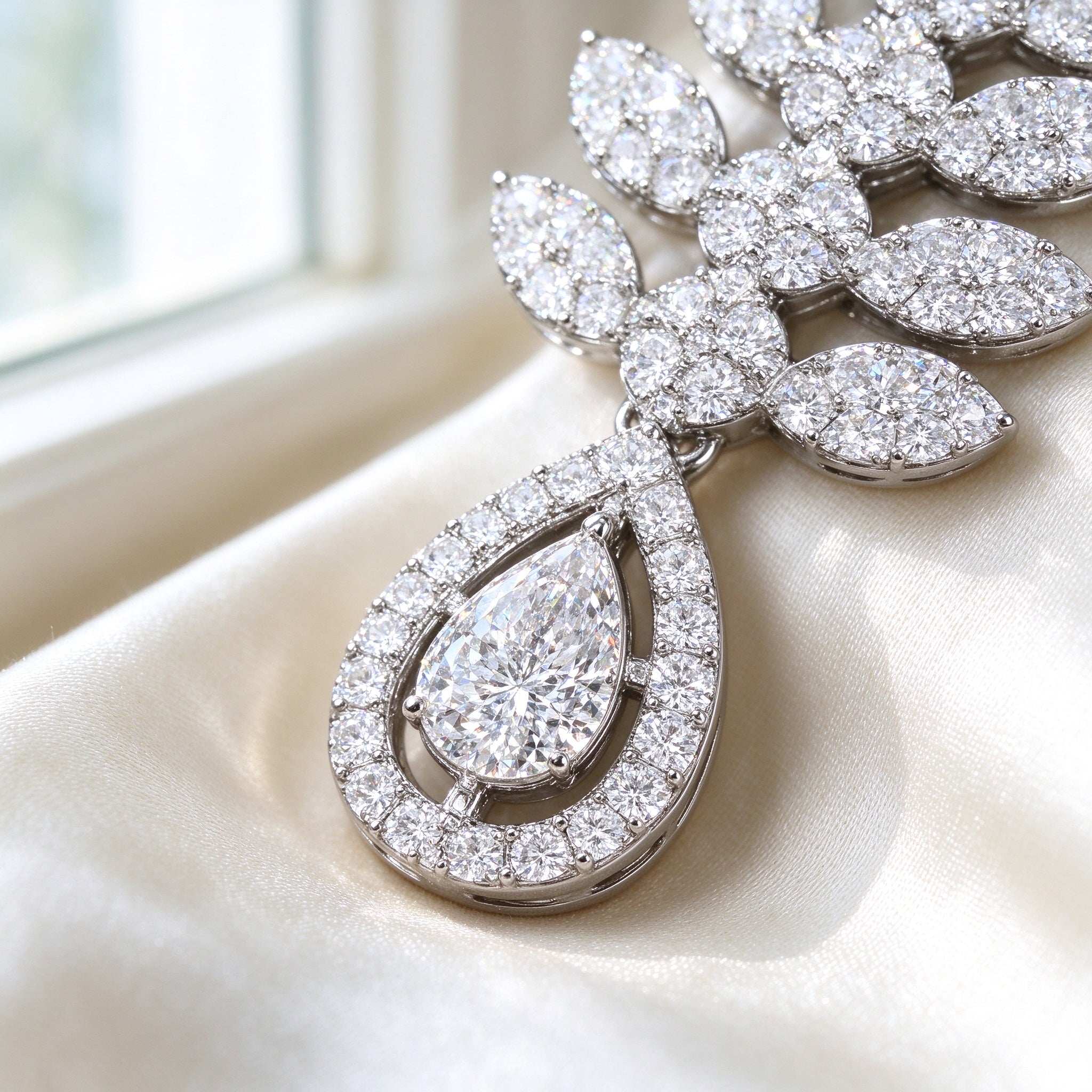 Macro close-up of the double-halo pear teardrop pendant and surrounding marquise-leaf pavé