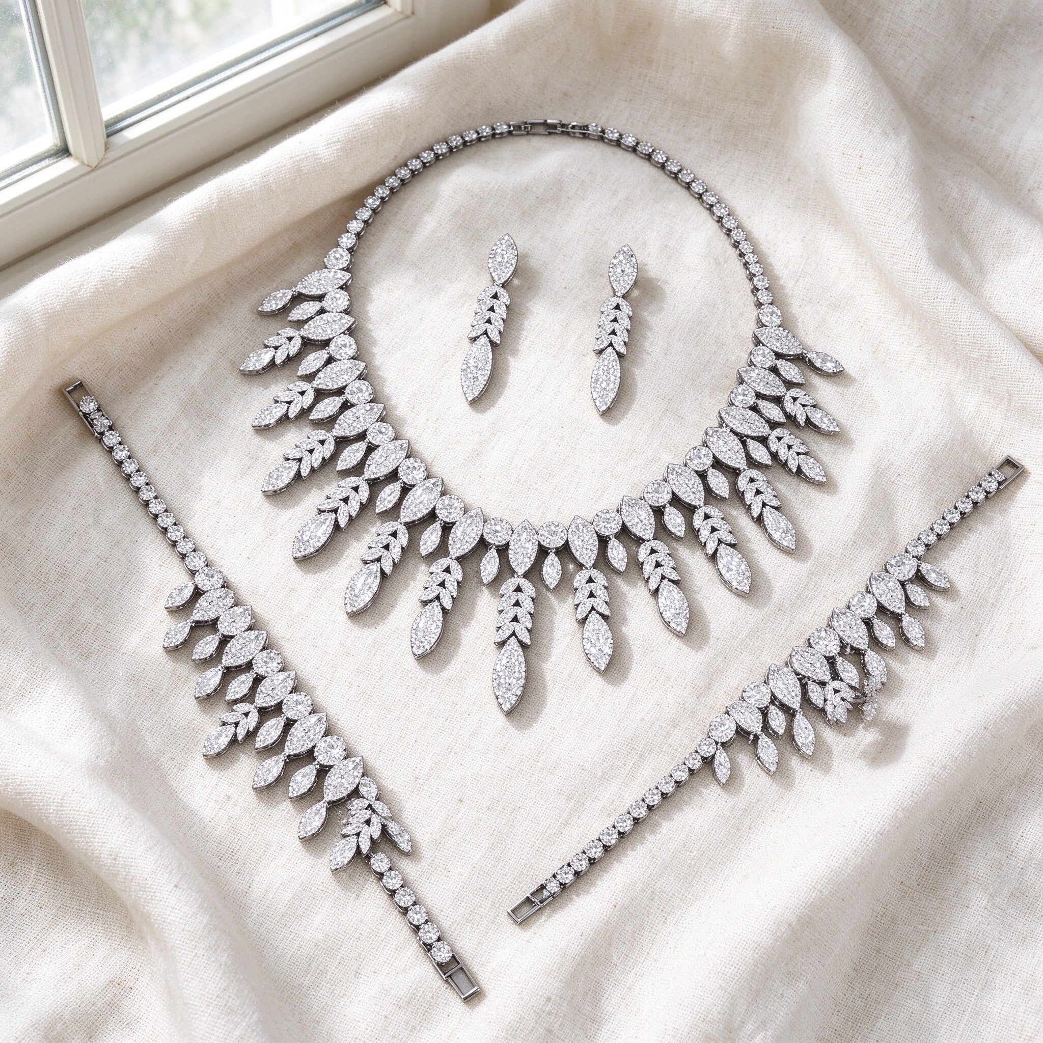 Top-down flat lay of The Luna Crystal Set two-piece clear CZ bridal set on warm ivory linen