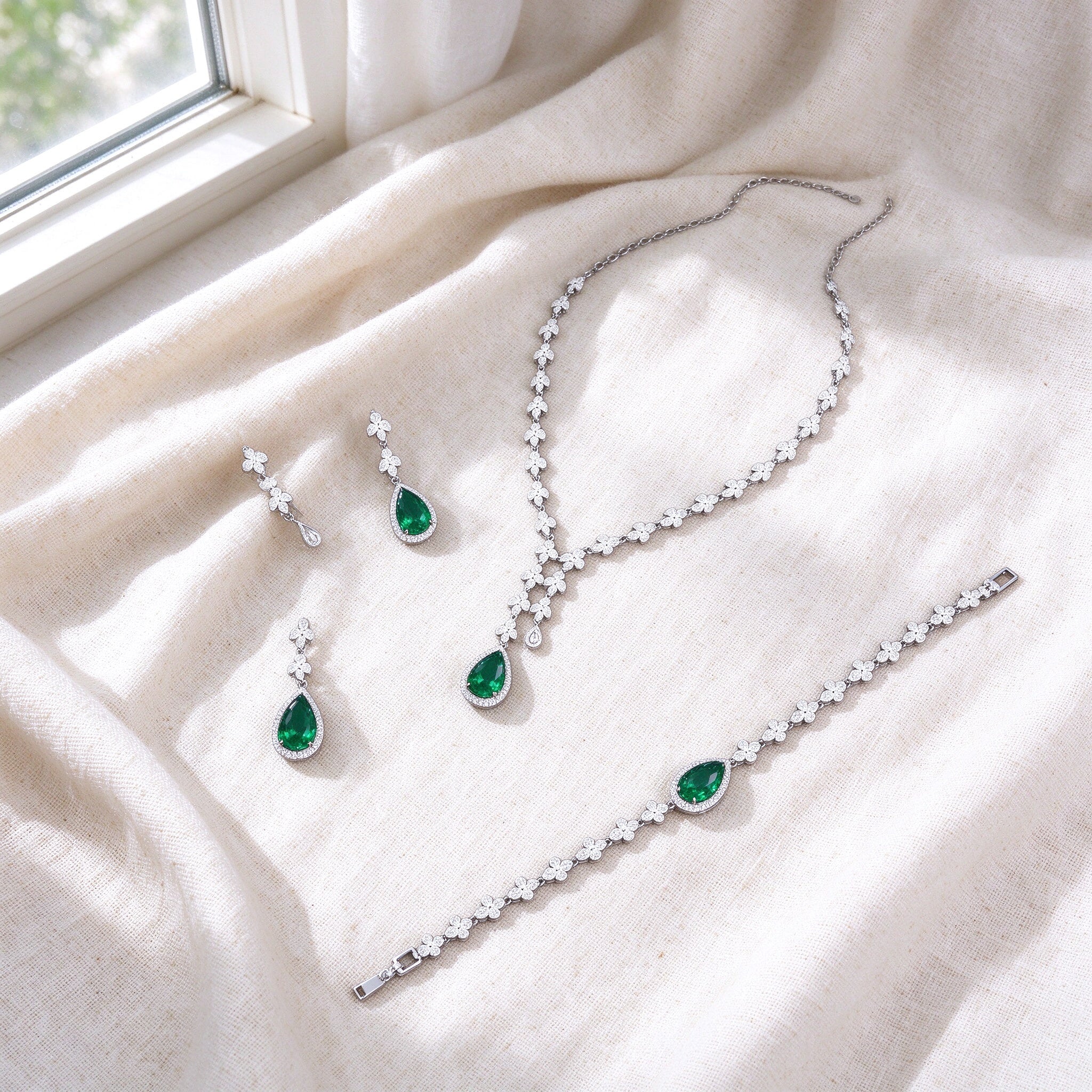 Overhead flat lay of The Magnolia Crystal Parure three pieces on soft ivory linen by a bright window