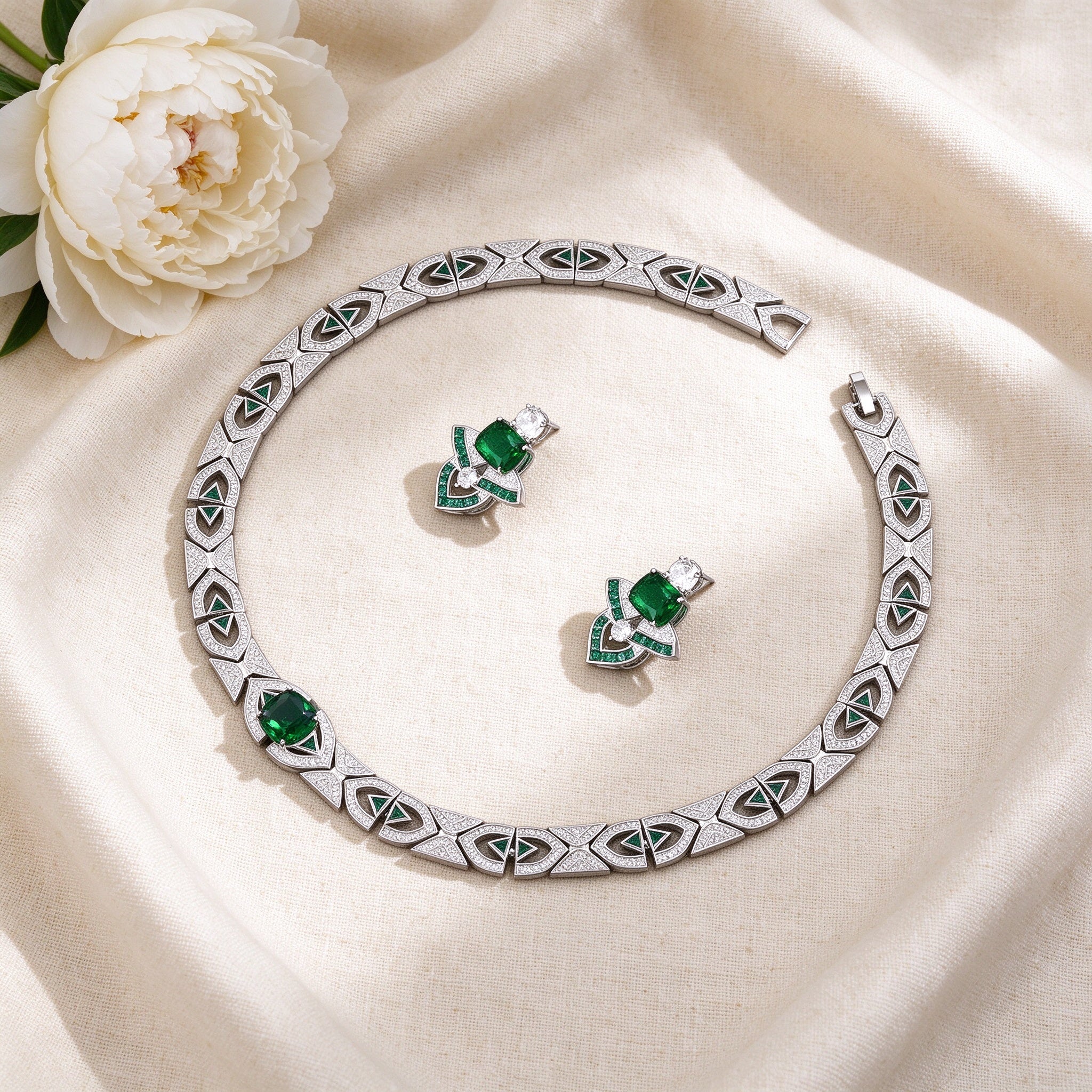 Flat lay of The Meteor Wedding Suite Art Deco necklace and earrings on ivory linen