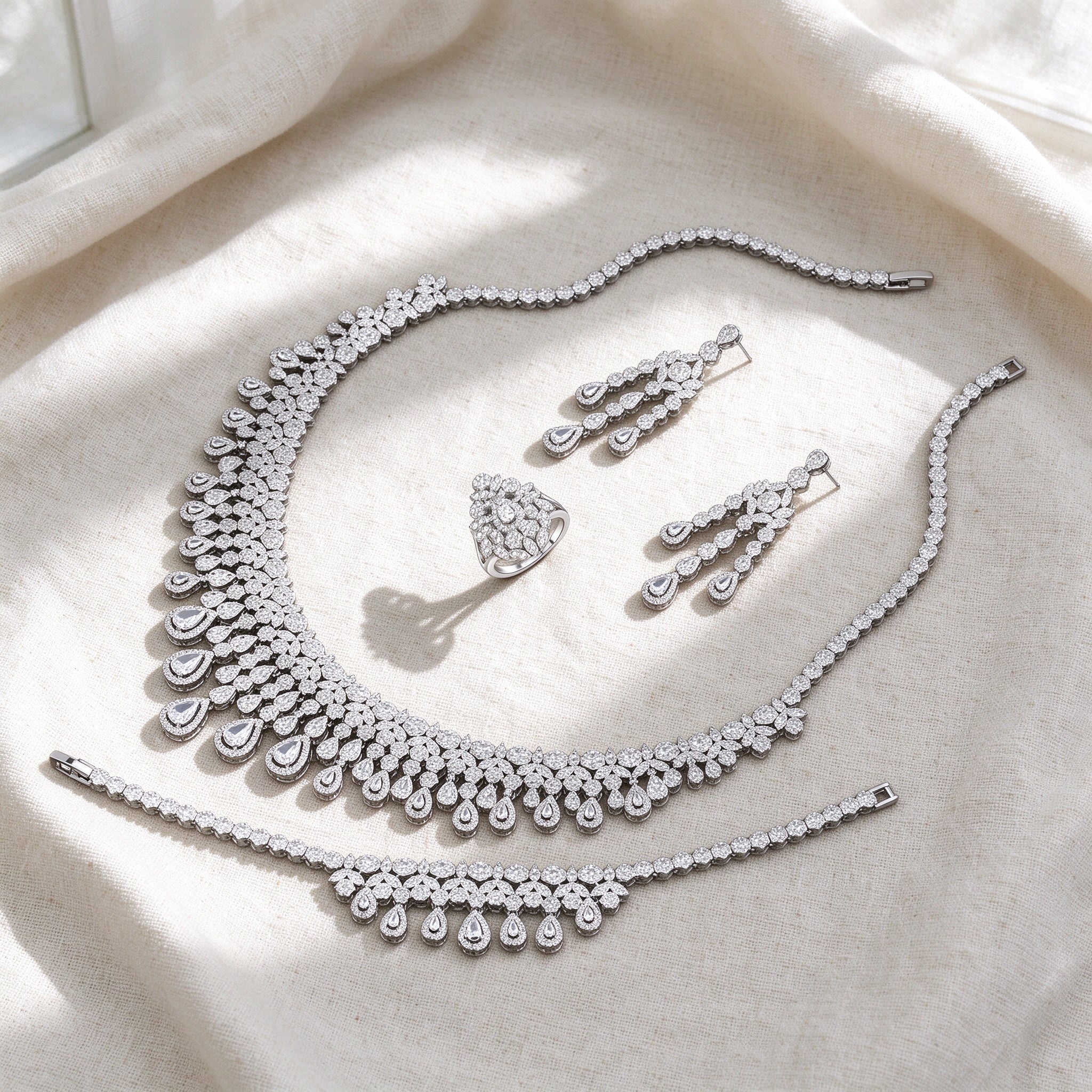 Top-down flat lay of The Moonlight Bridal Set three-piece silver pavé bridal set on warm ivory linen