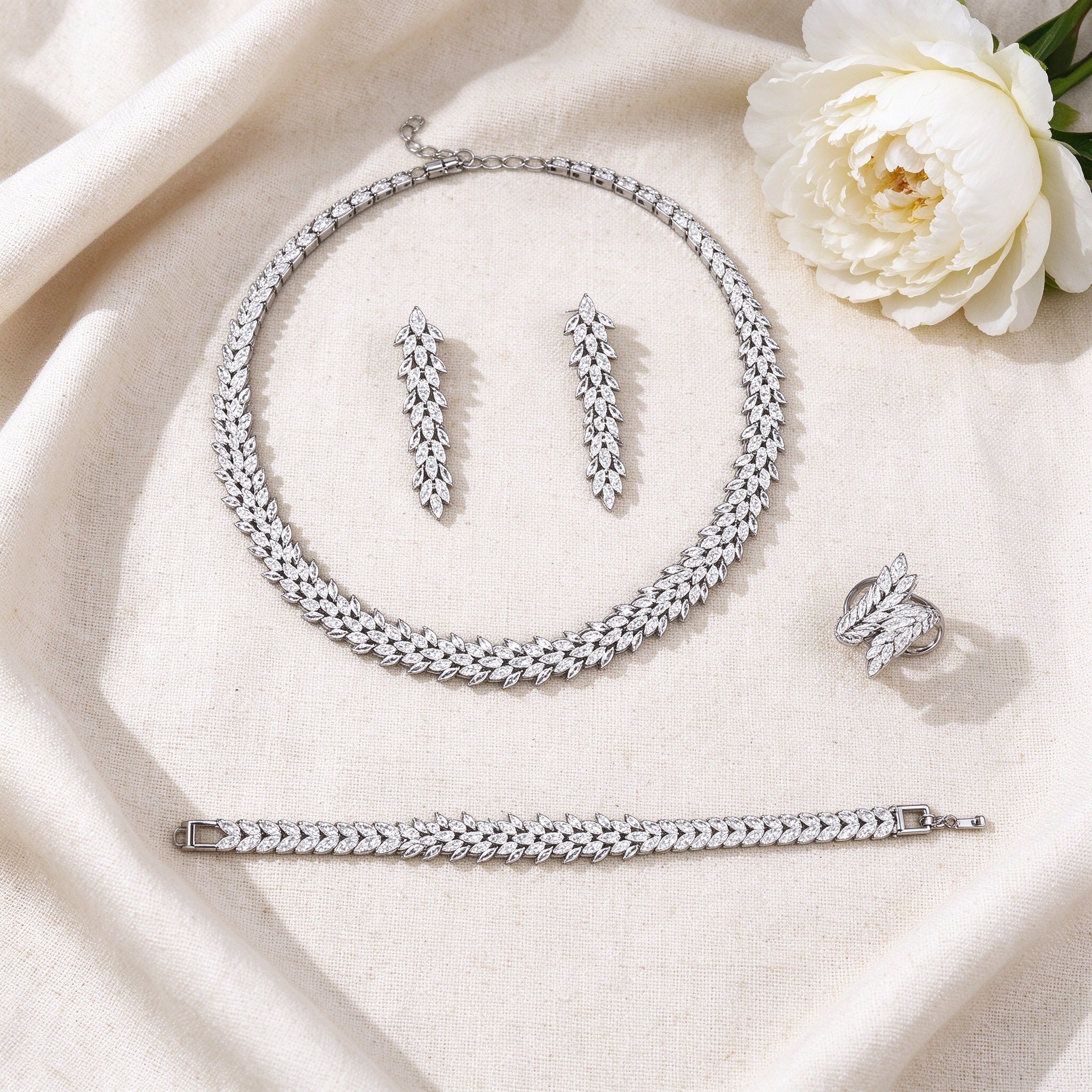 Top-down flat lay of The Nova Crystal Parure two-piece baguette CZ bridal set on warm ivory linen