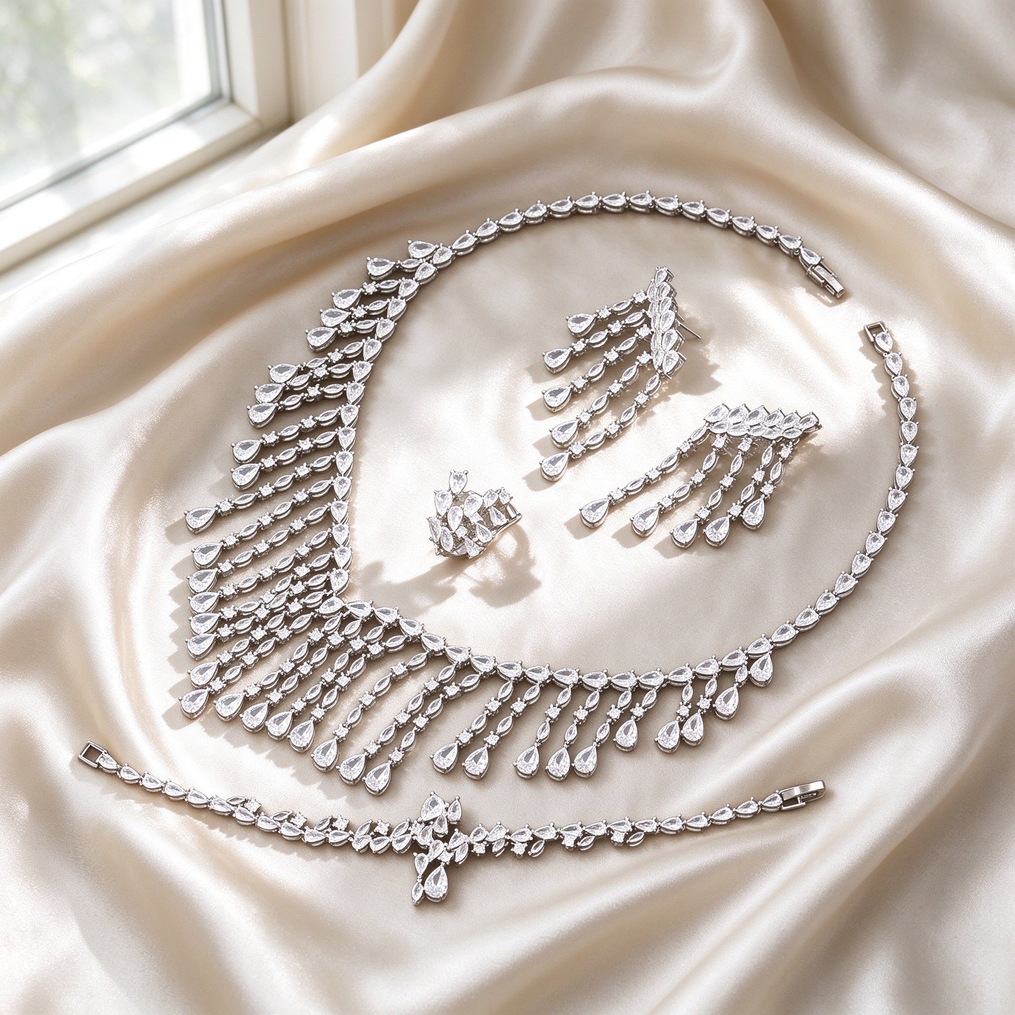 Flat lay of The Oriana Crystal Parure four-piece set on ivory silk satin