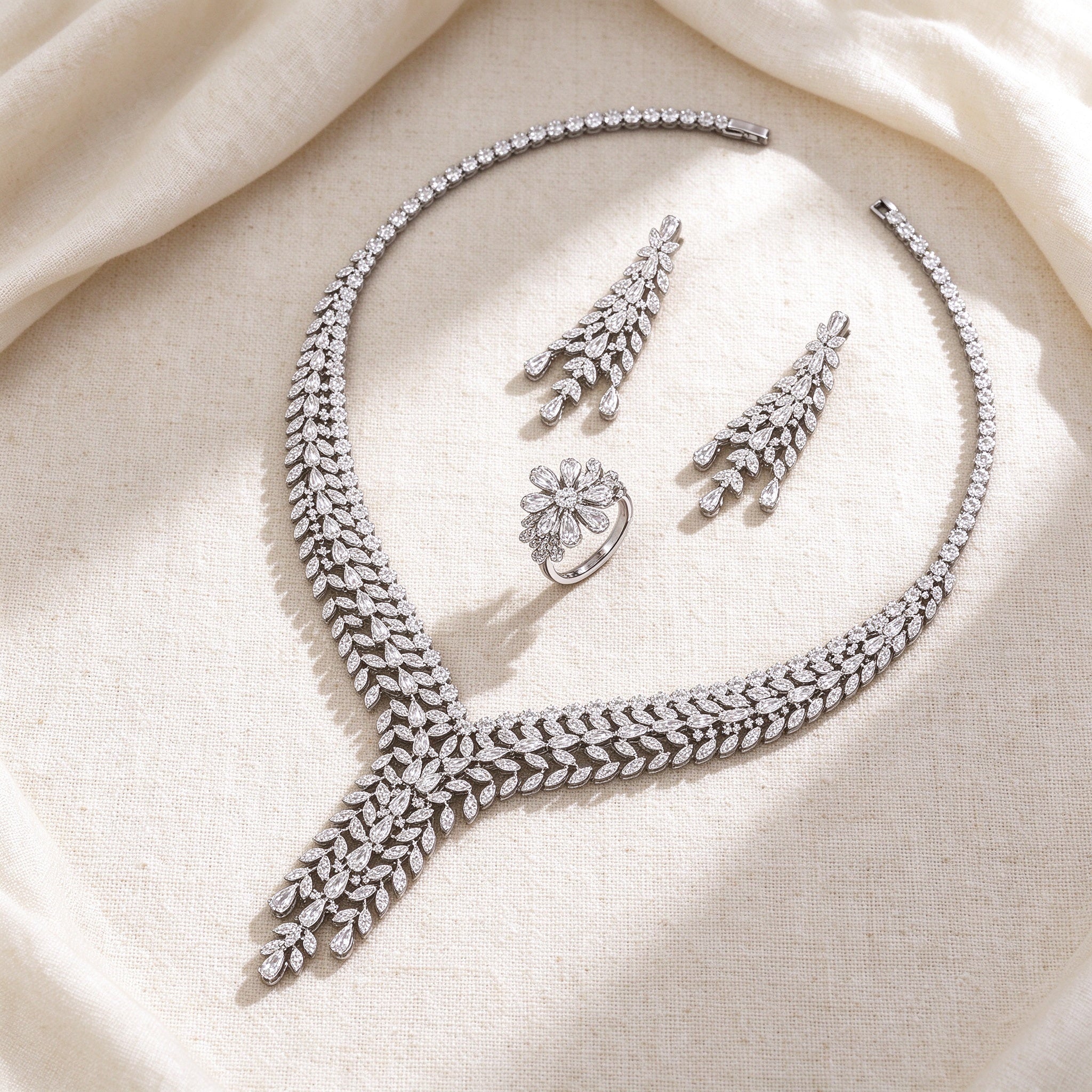 Flat lay of The Peyton Bridal Set necklace, earrings and floral cluster ring on ivory linen
