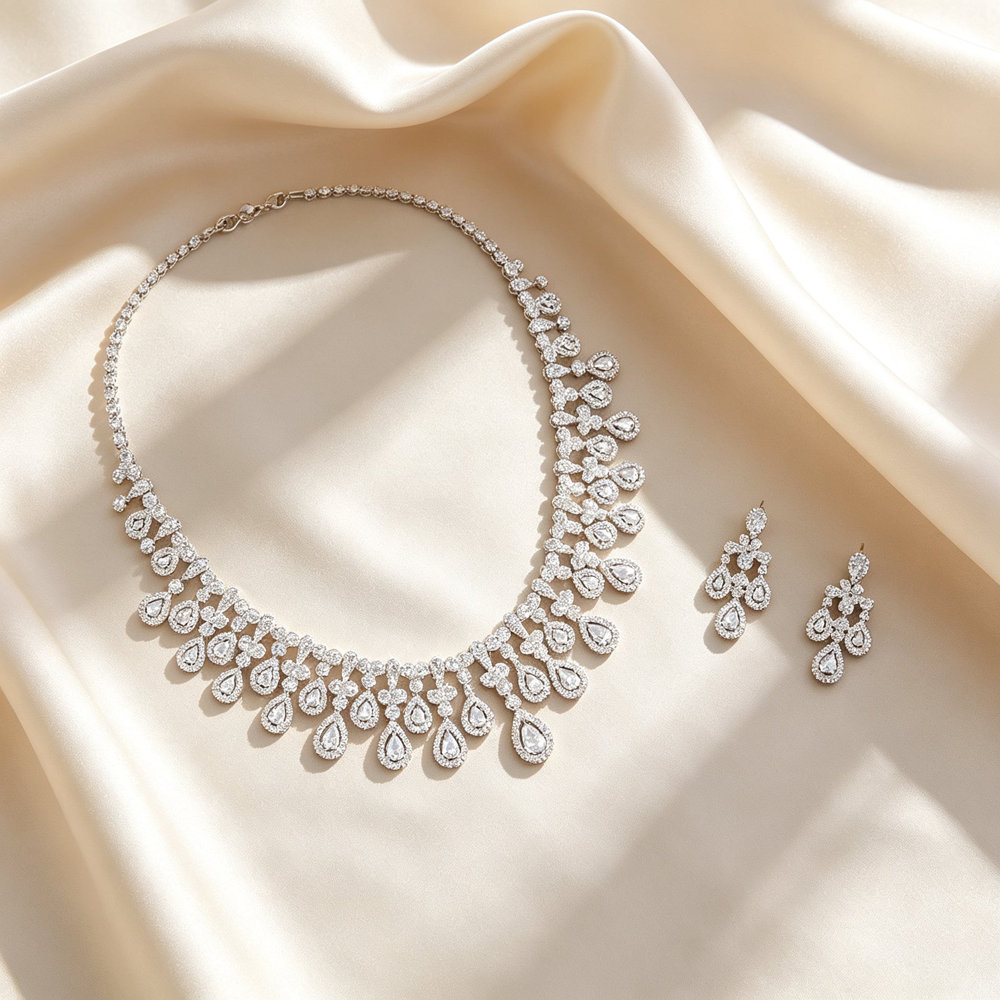 Flat lay of The Rosalie Bridal Set necklace and earrings on draped ivory champagne silk
