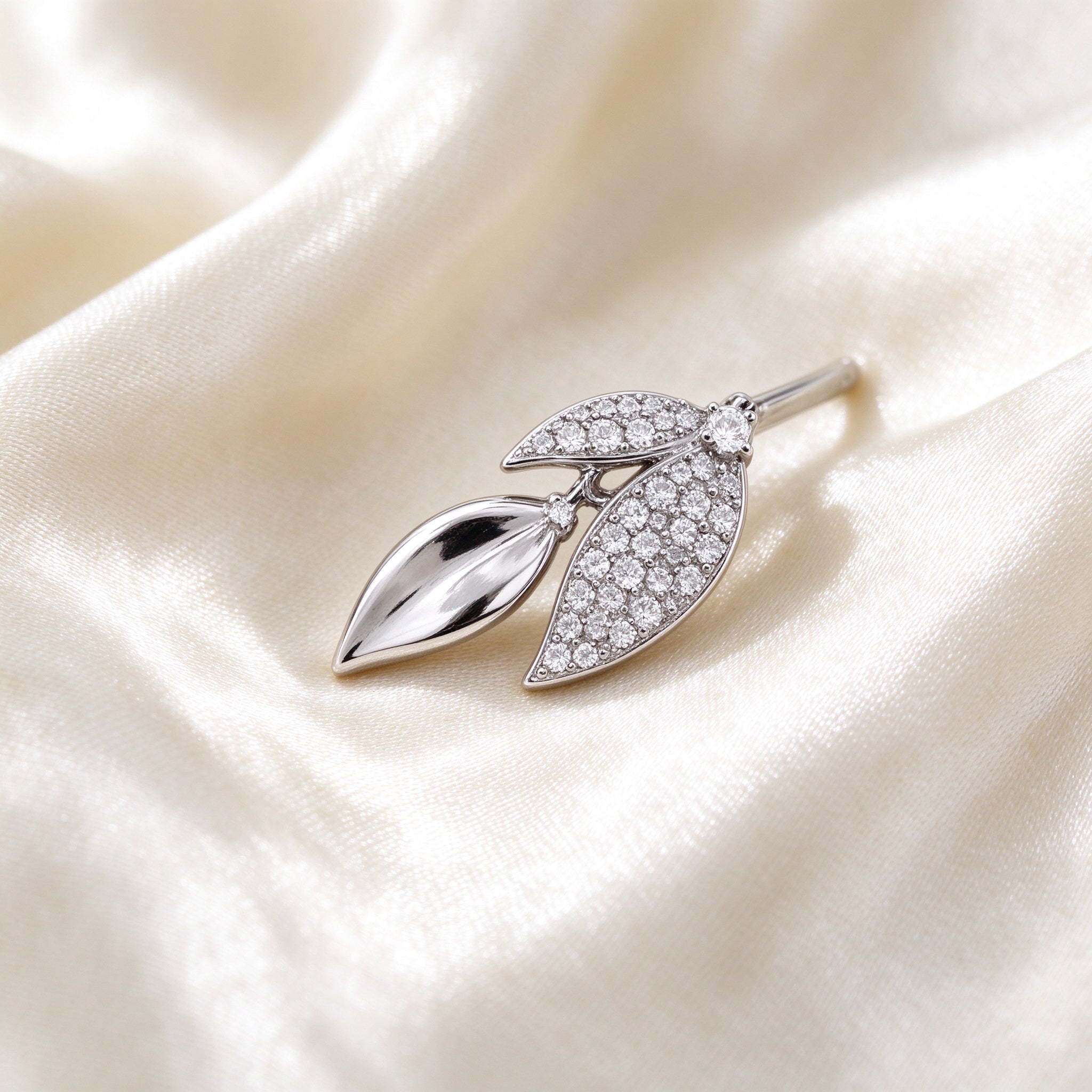 Macro detail of The Stella Bridal Parure alternating polished marquise leaf and pavé cubic-zirconia leaf on ivory silk