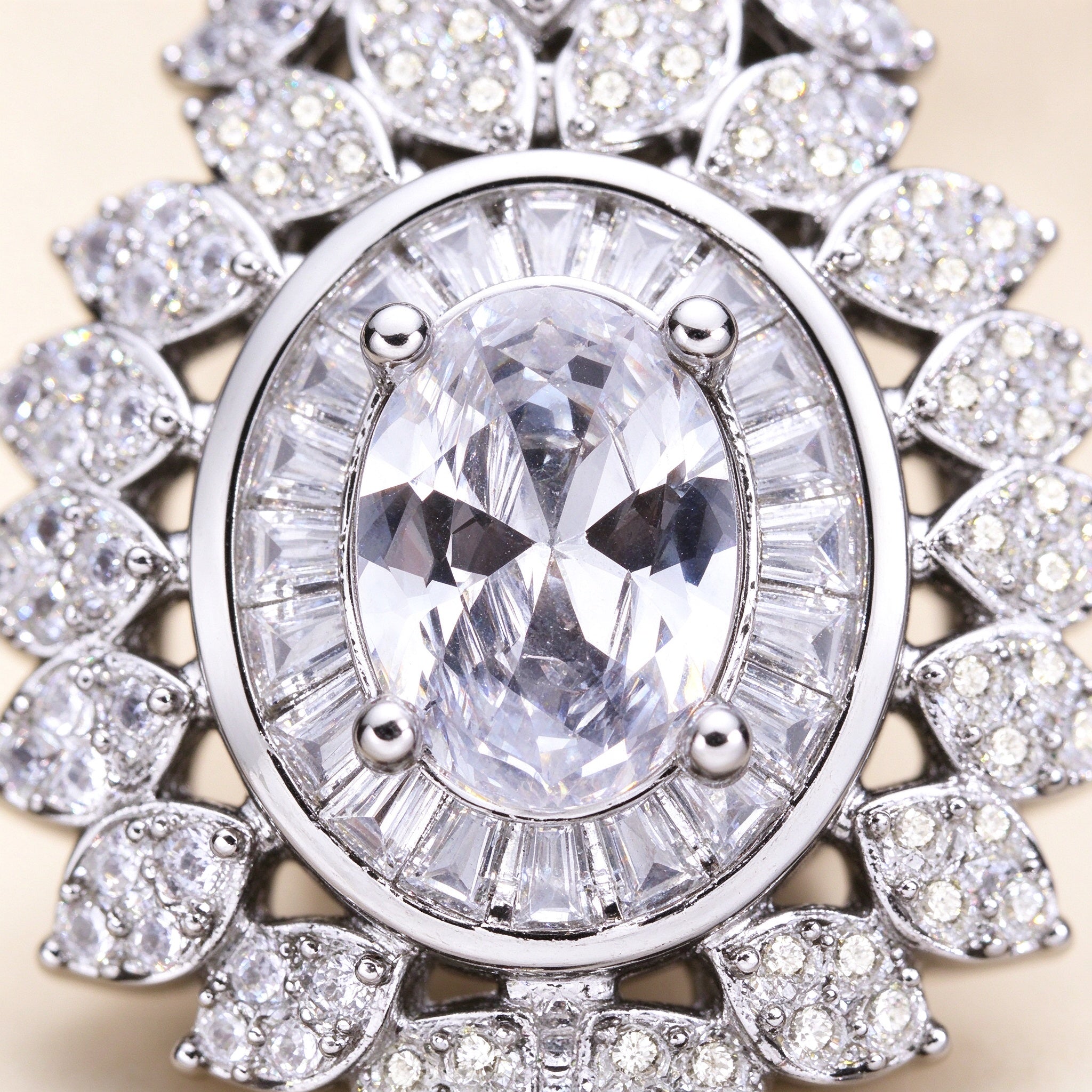Macro close-up of an oval clear cubic zirconia surrounded by a baguette-cut halo and marquise-leaf CZ
