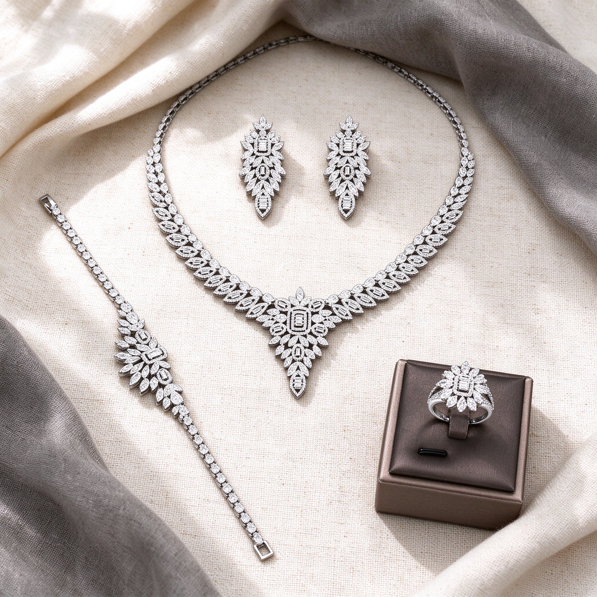 Overhead flat lay of The Tiara four-piece silver-tone CZ bridal suite on cream linen