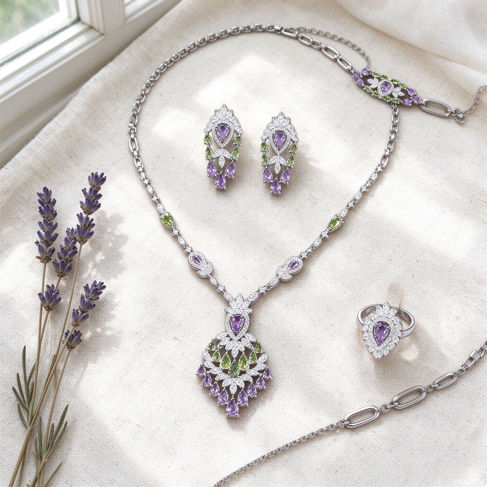 Overhead flat lay of The Wheat Crystal Parure necklace, earrings, bracelet and ring on ivory linen with dried lavender