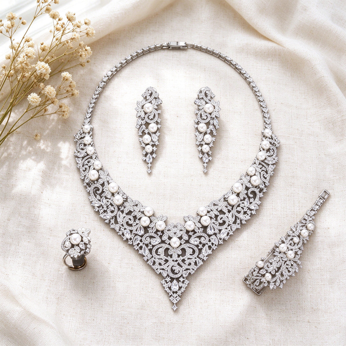 Overhead flat lay of The Grain Bridal Set necklace, earrings, bracelet and ring on ivory linen