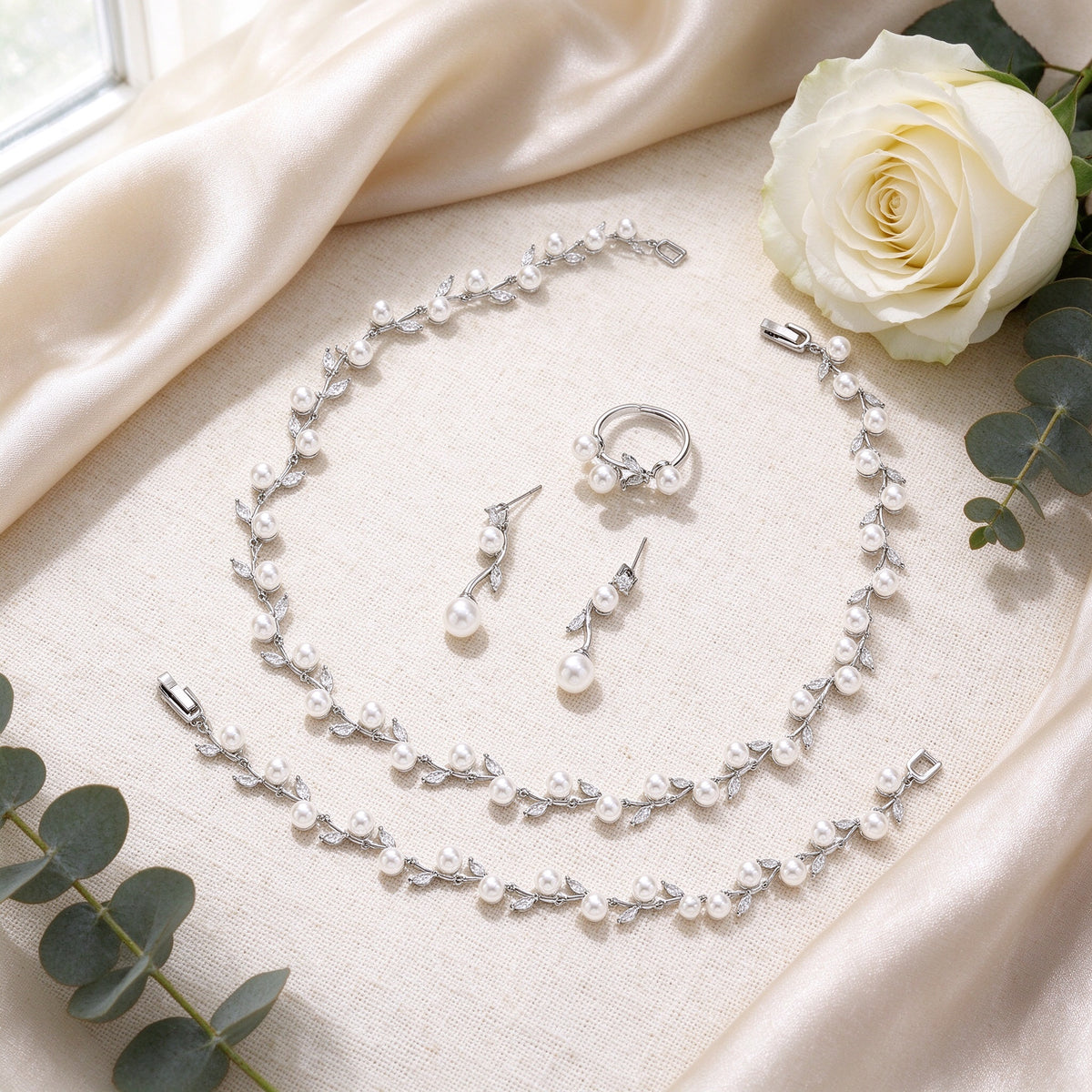Flat lay of The Alpine Crystal Parure pearl jewelry set on ivory linen