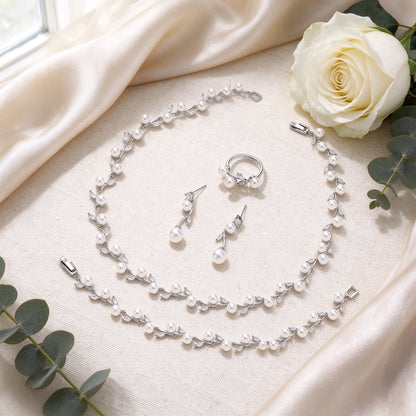 Flat lay of The Alpine Crystal Parure pearl jewelry set on ivory linen