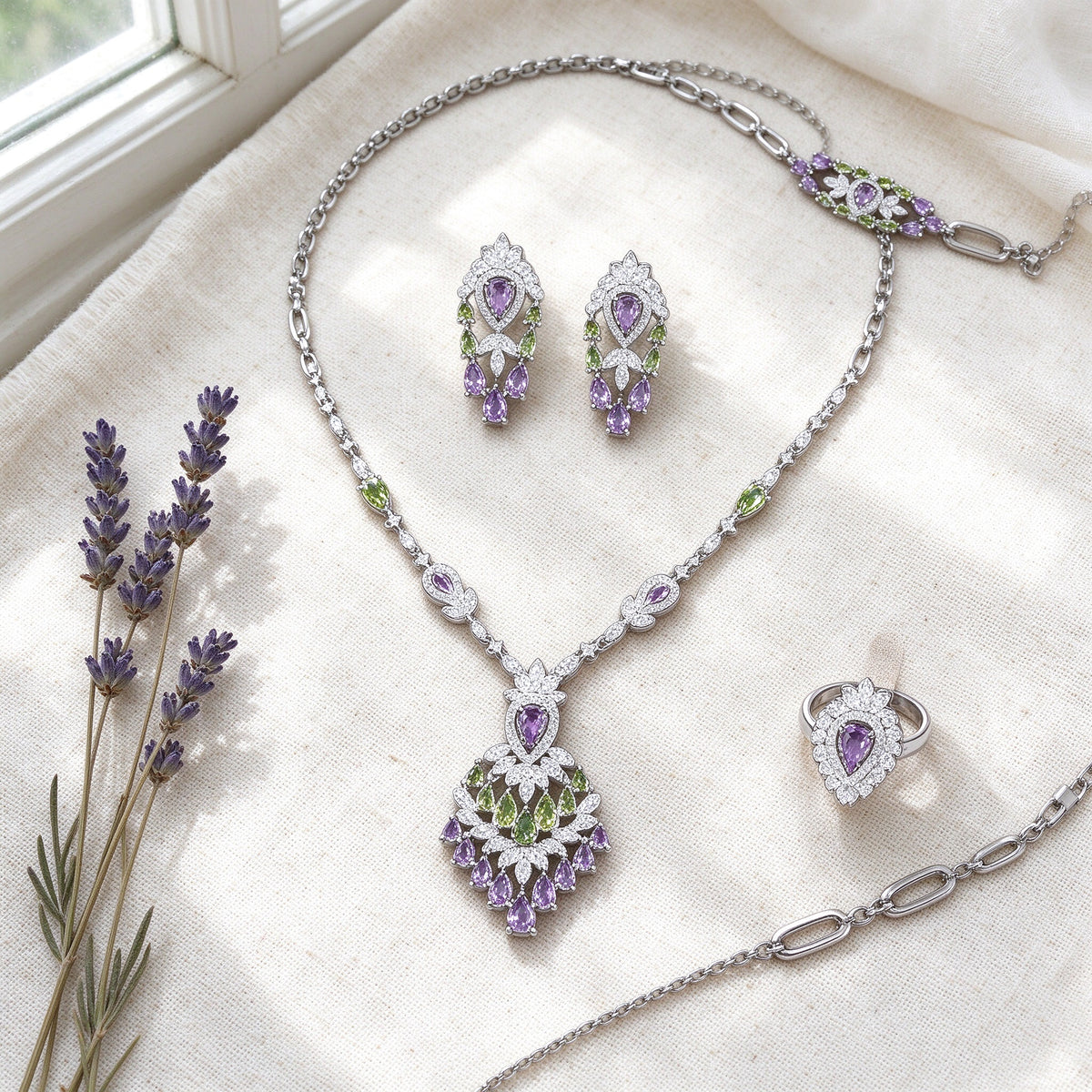 Overhead flat lay of The Wheat Crystal Parure necklace, earrings, bracelet and ring on ivory linen with dried lavender