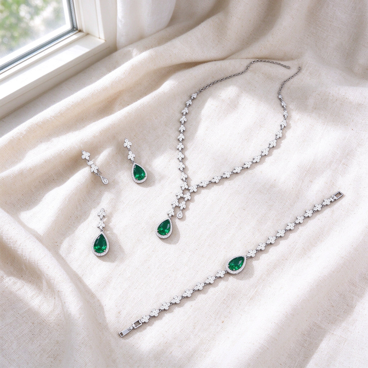 Overhead flat lay of The Magnolia Crystal Parure three pieces on soft ivory linen by a bright window