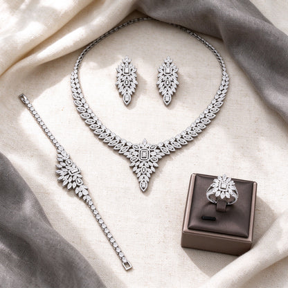 Overhead flat lay of The Tiara four-piece silver-tone CZ bridal suite on cream linen