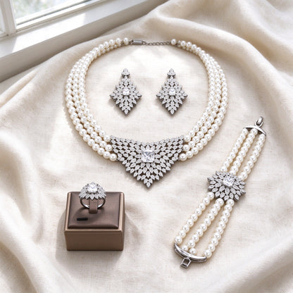 Flat lay of The Vale Bridal Parure on ivory linen — necklace, earrings, bracelet, ring