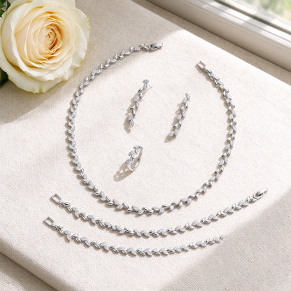 Flat lay of The Summit Wedding Suite necklace, earrings, bracelet and ring with ivory rose