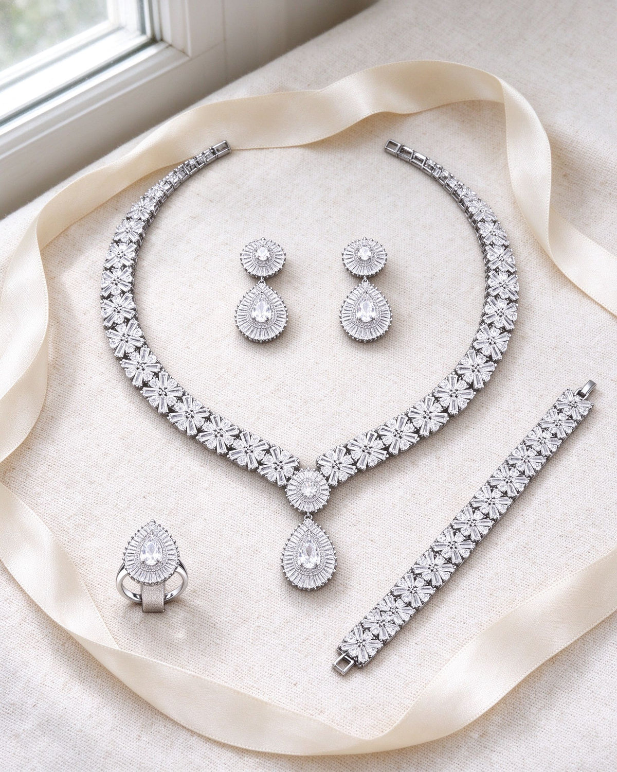 The Root Wedding Suite necklace, earrings, bracelet and ring flat-laid on ivory linen