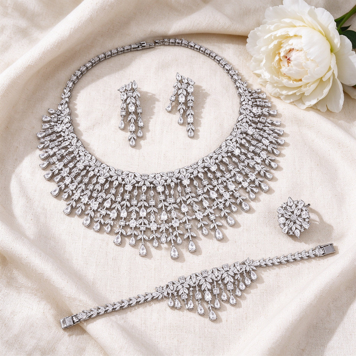 Flat lay of The Comet Crystal Parure four-piece bridal jewelry set on ivory linen