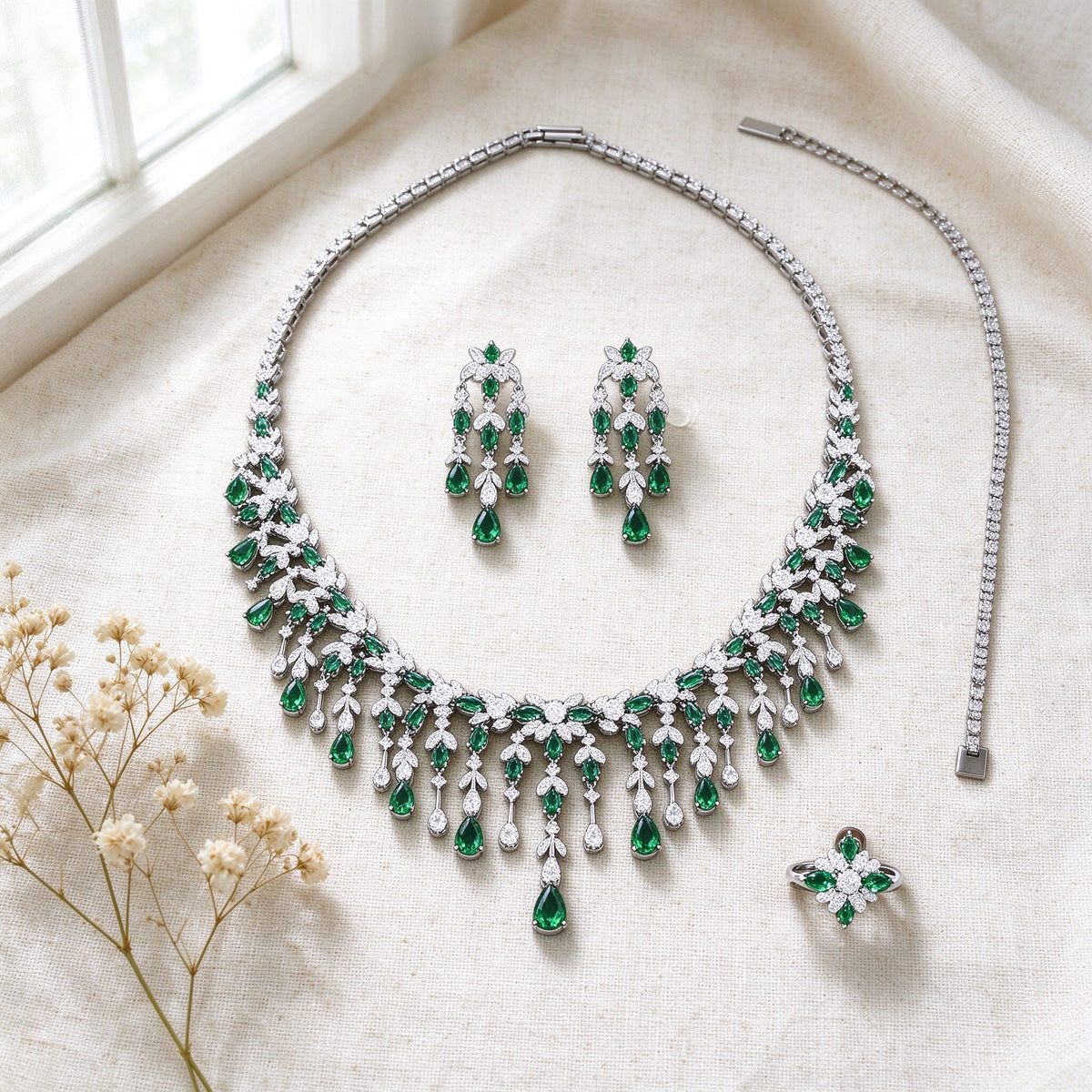 Overhead flat lay of The Sheaf Wedding Suite necklace, earrings, bracelet and ring on ivory linen