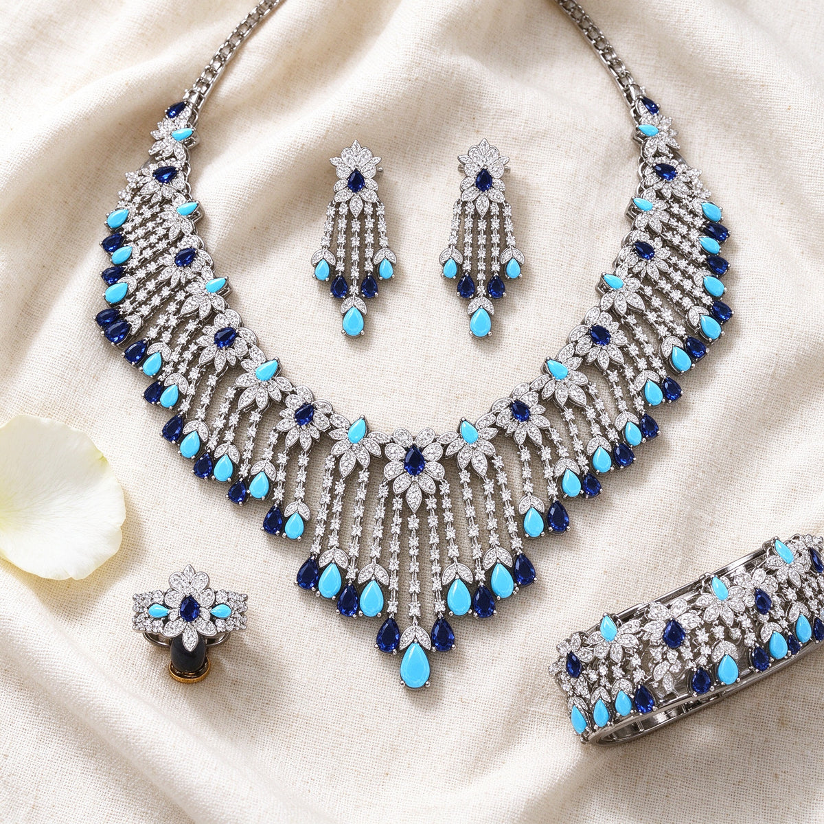 Flat lay of The Celestine Bridal Parure necklace, earrings, bracelet and ring on linen