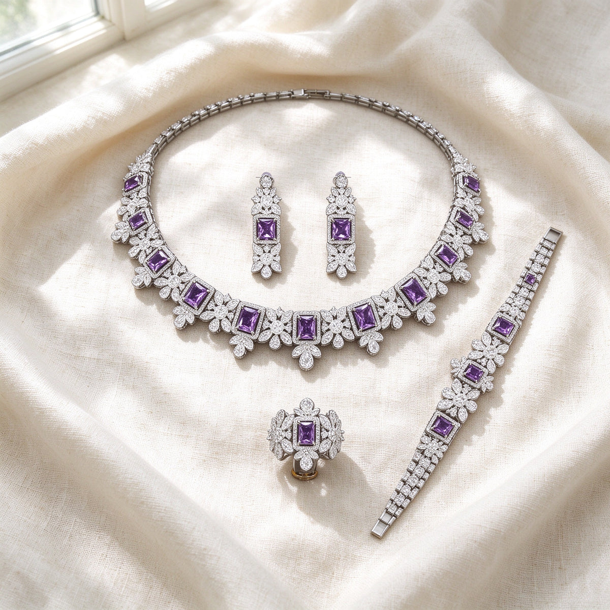 Flat lay of The Storm Wedding Suite on ivory linen — necklace, earrings, bracelet, ring