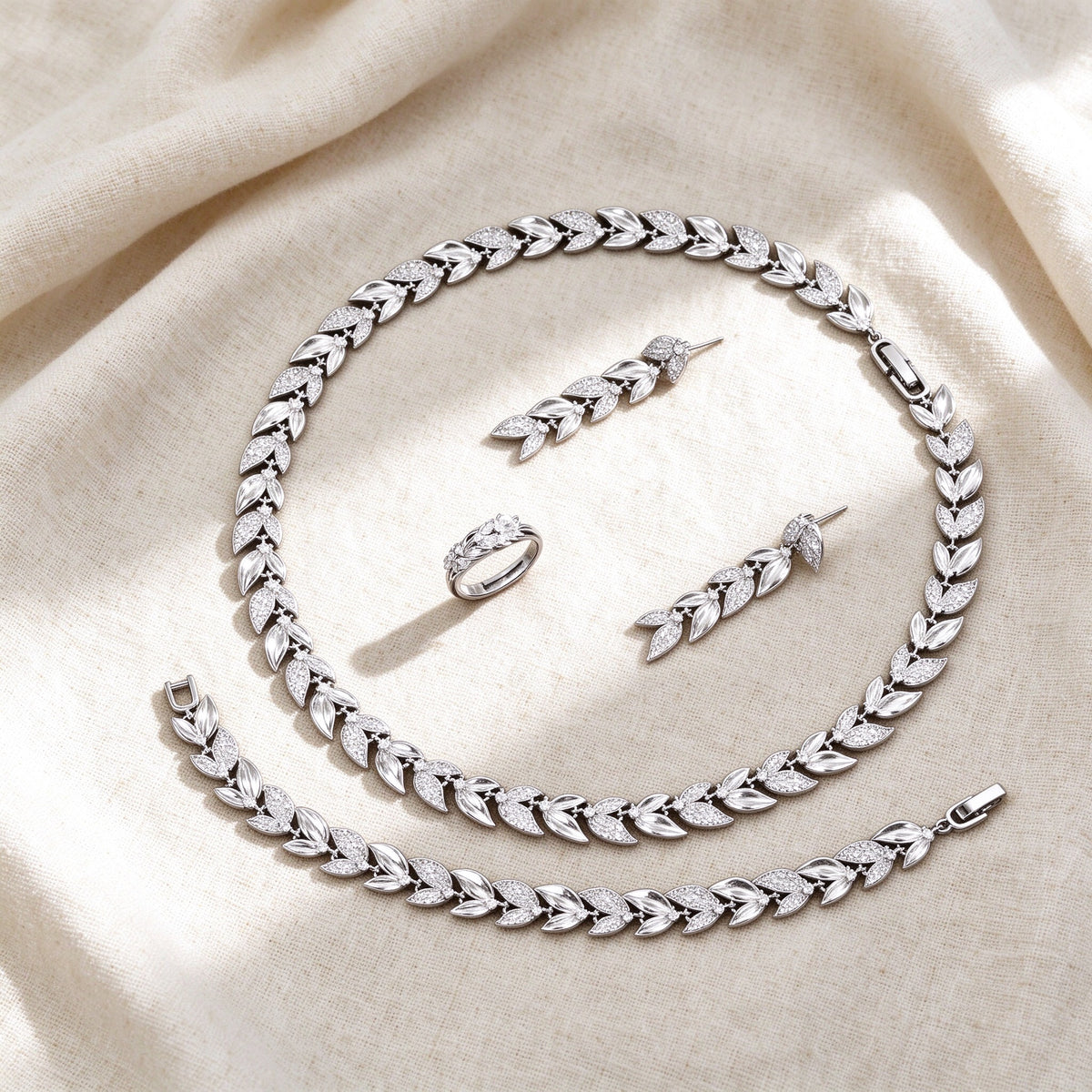 Top-down flat lay of The Stella Bridal Parure four-piece laurel-leaf botanical bridal set on warm ivory linen