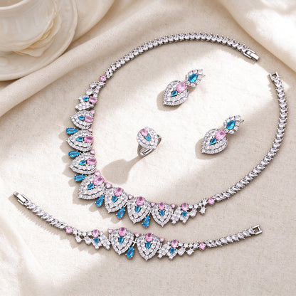 Flat lay of The Wren Wedding Suite necklace, earrings, bracelet and pink-blue cluster ring on ivory linen
