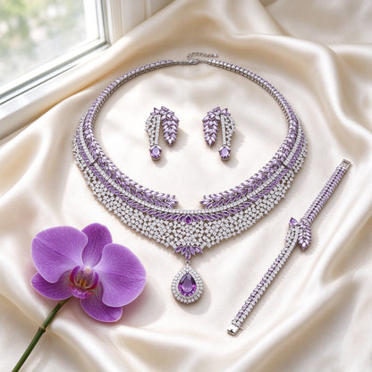 Overhead flat lay of The Branch purple CZ bridal set on ivory silk with an orchid