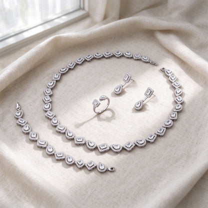 Top-down flat lay of The Celestia Wedding Suite four-piece halo CZ bridal set on warm ivory linen