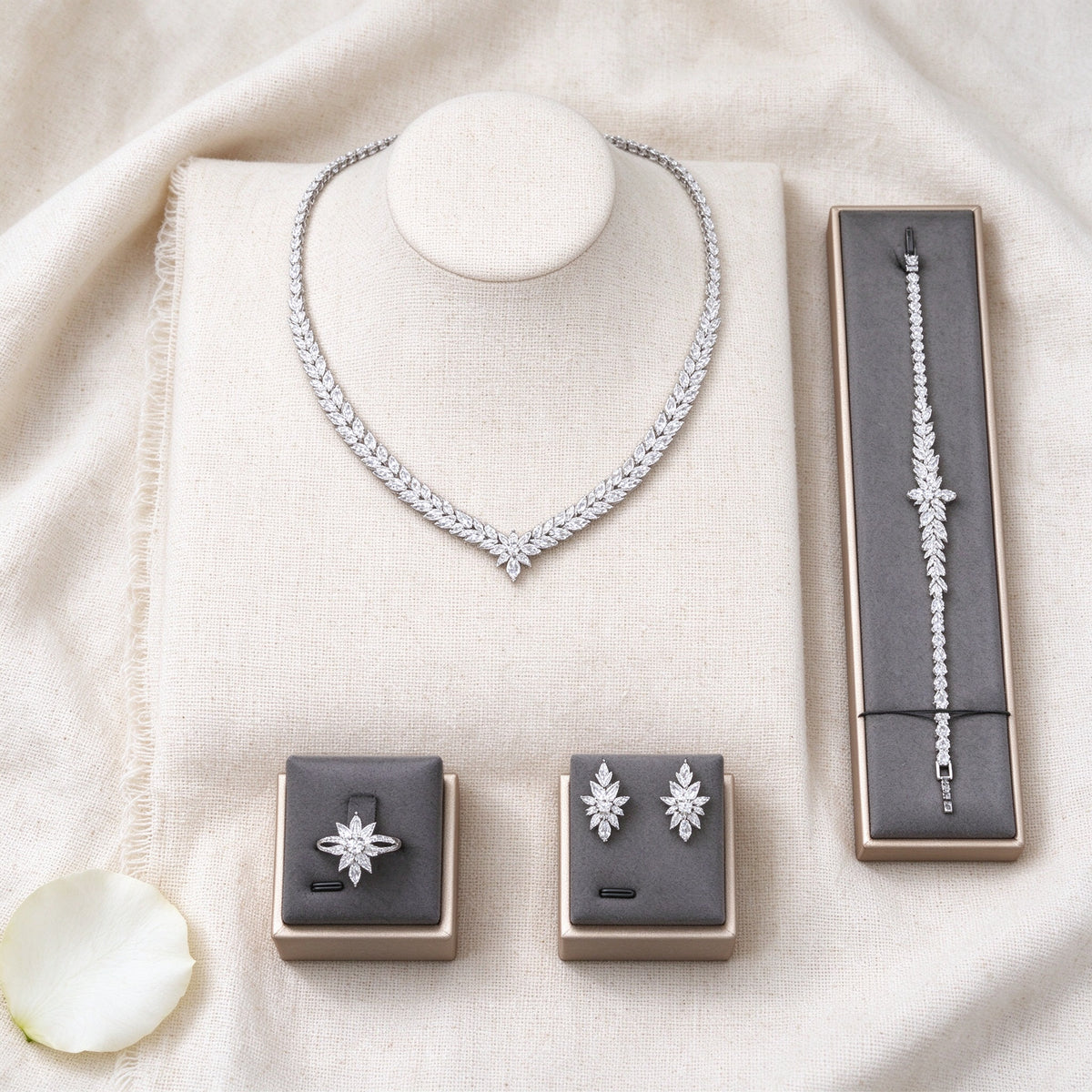 Top-down flat lay of The Coronet Bridal Set four-piece clear CZ leaf bridal set on ivory linen