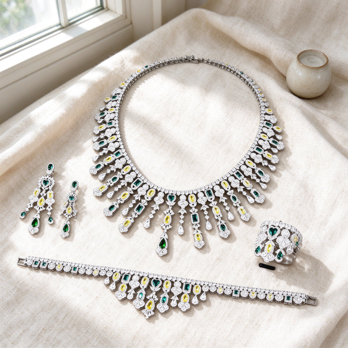 Overhead flat lay of The Dahlia Crystal Parure four pieces on warm cream linen