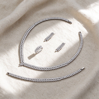 Flat lay of the silver CZ laurel leaf four-piece bridal set on cream linen