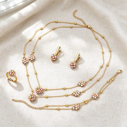 Top-down flat lay of The Sunbeam Crystal Parure four-piece dainty gold floral set on warm ivory linen
