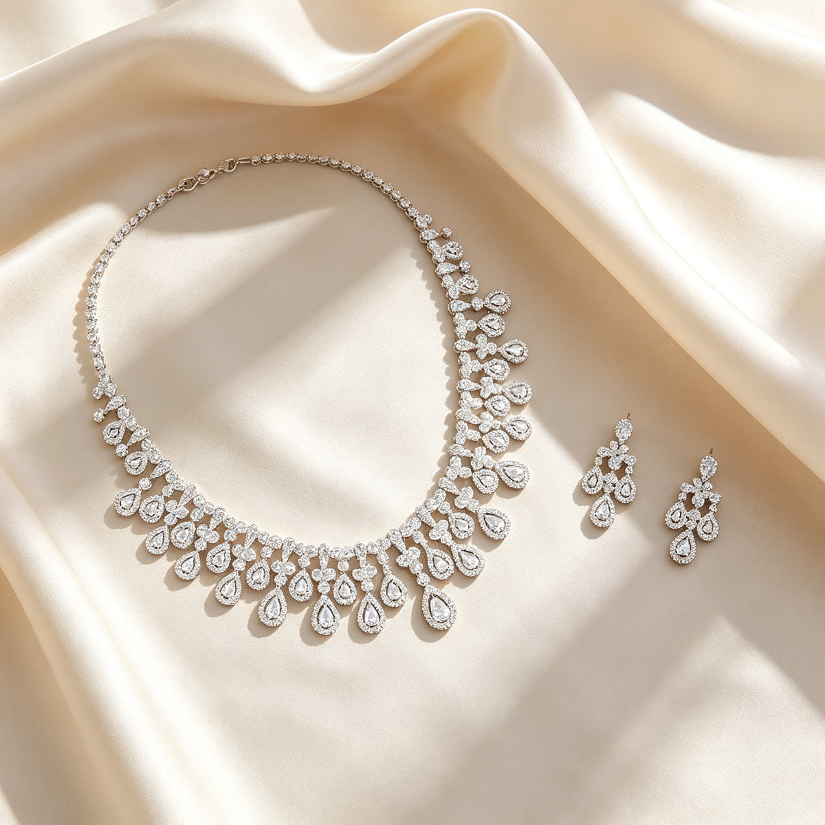 Flat lay of The Rosalie Bridal Set necklace and earrings on draped ivory champagne silk