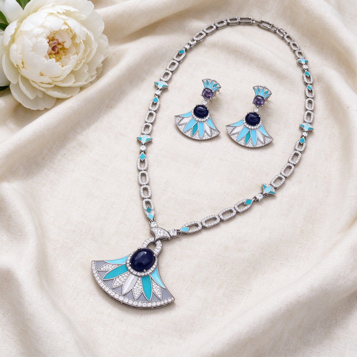Flat lay of The Starlight Bridal Parure long necklace and fan earrings on ivory linen