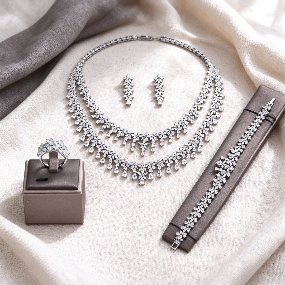 Overhead flat lay of The Crest four-piece silver-tone CZ bridal set on cream linen