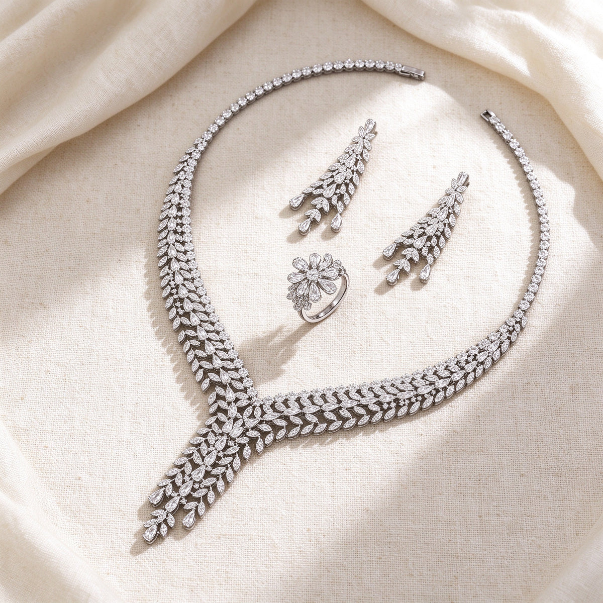 Flat lay of The Peyton Bridal Set necklace, earrings and floral cluster ring on ivory linen