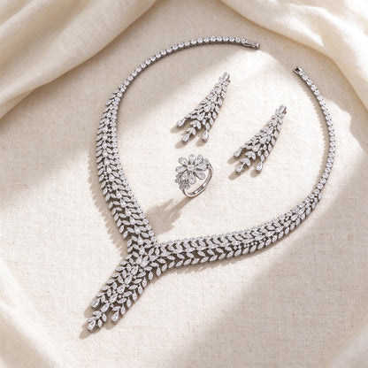 Flat lay of The Peyton Bridal Set necklace, earrings and floral cluster ring on ivory linen