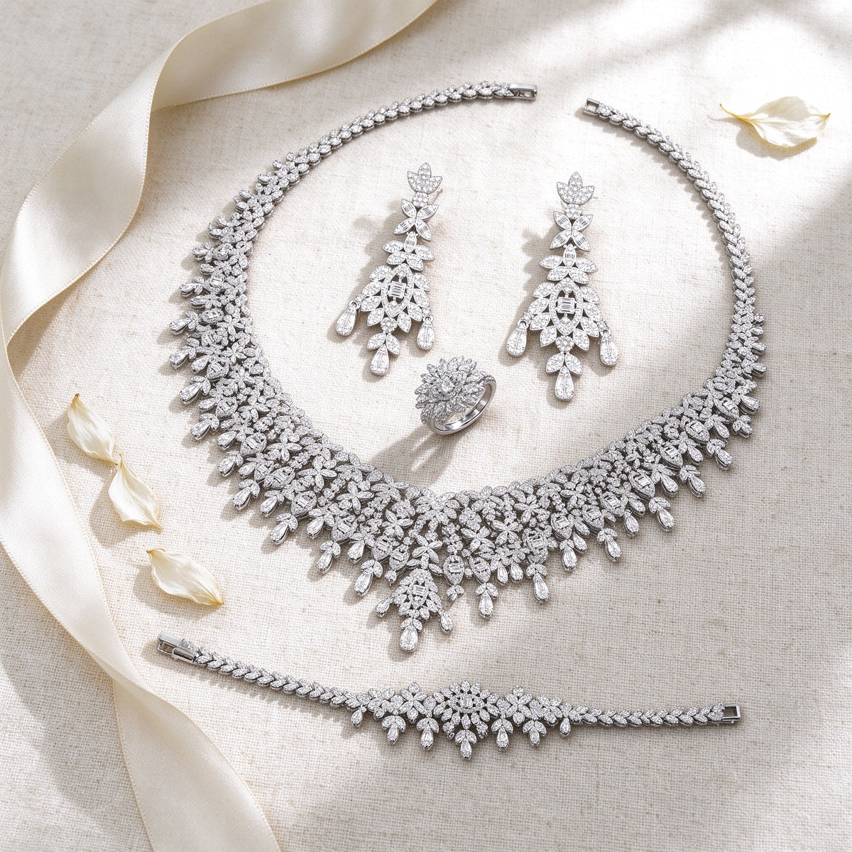 Styled flat lay of The Selene Bridal Parure necklace, earrings, bracelet and ring on cream linen with an ivory ribbon