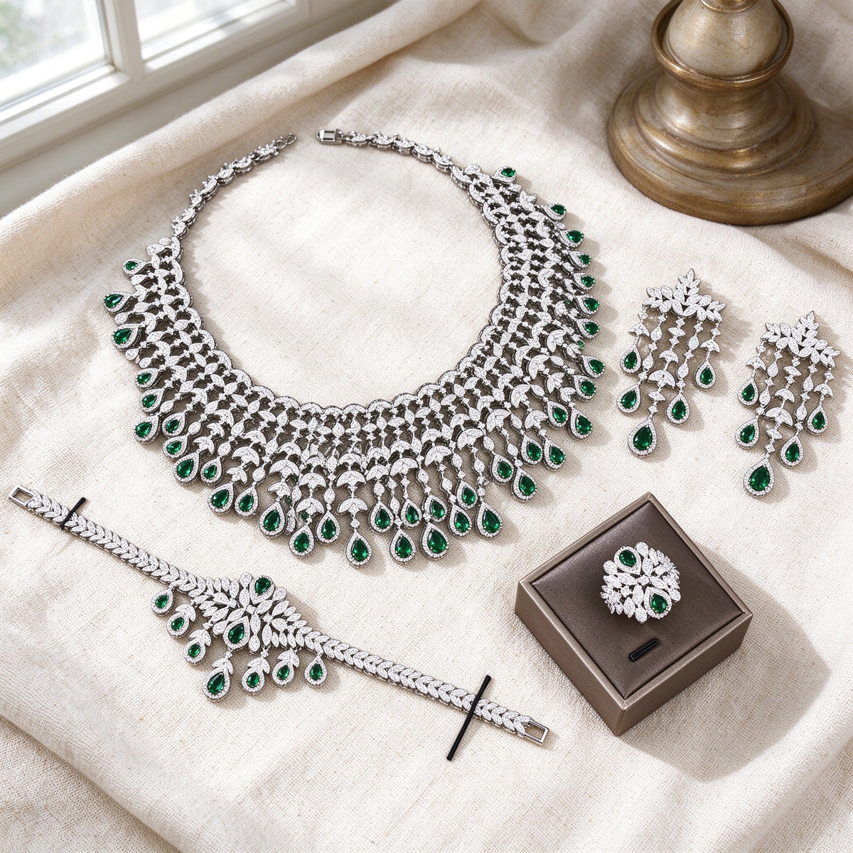 Flat lay of complete Sage crystal parure on warm ivory linen