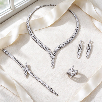 Styled flat lay of The Elowen Wedding Suite necklace, earrings, bracelet and ring on cream linen with an ivory ribbon