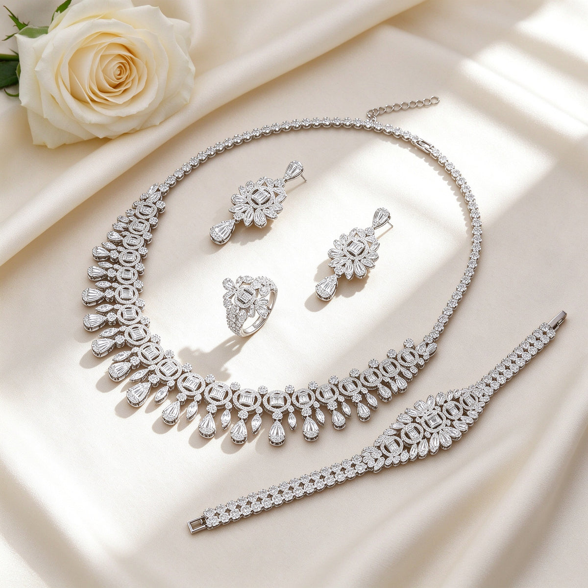 Overhead flat lay of The Vine silver CZ bridal set on ivory silk with a cream rose