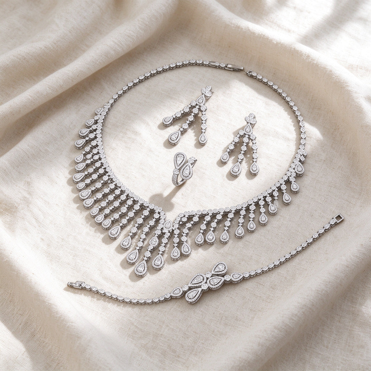 Flat lay of complete Ember bridal jewelry set on warm ivory linen