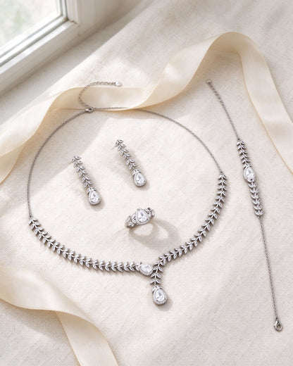 The Stem Crystal Parure necklace, earrings, bracelet and ring flat-laid on ivory linen