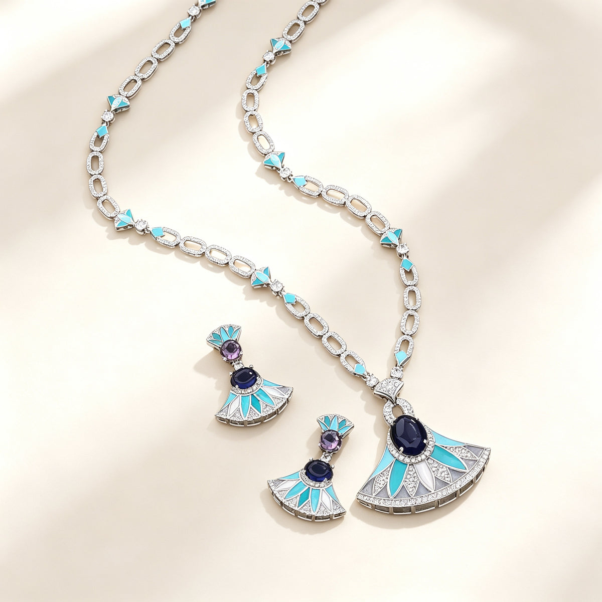 The Evangeline Crystal Suite — silver-tone long fan pendant necklace and matching turquoise enamel drop earrings on an ivory background