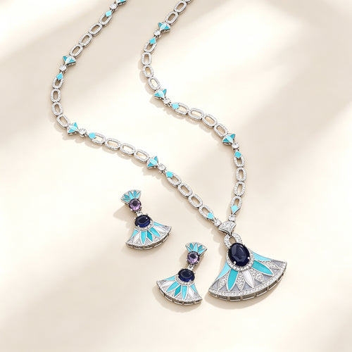 The Evangeline Crystal Suite — silver-tone long fan pendant necklace and matching turquoise enamel drop earrings on an ivory background