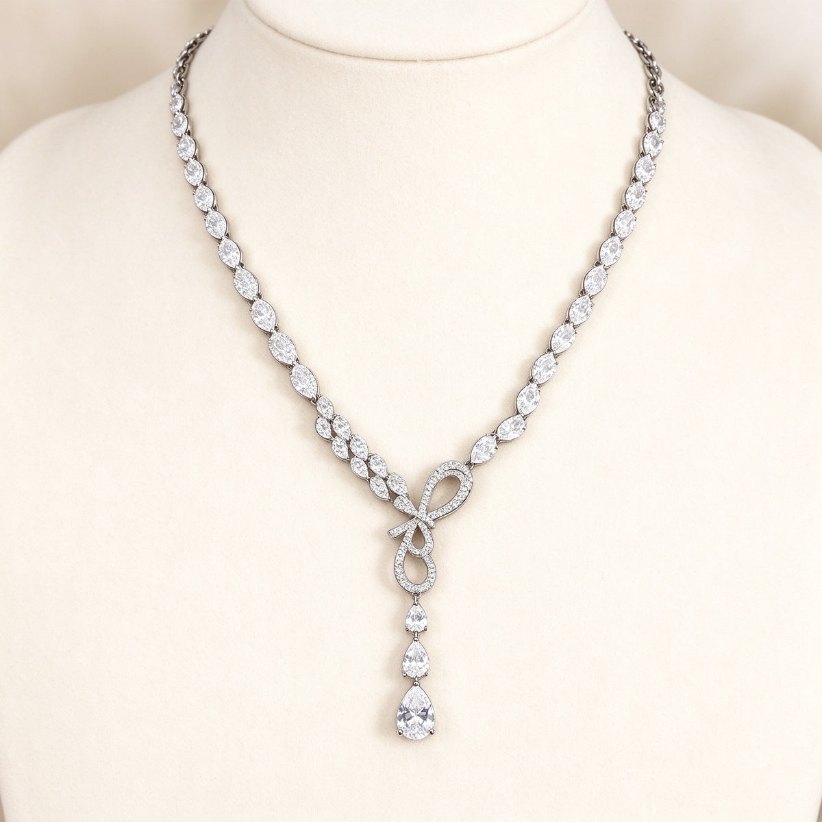 The Cameron Bridal Set – silver-tone pavé CZ ribbon-loop Y-necklace and pear-drop earrings on ivory